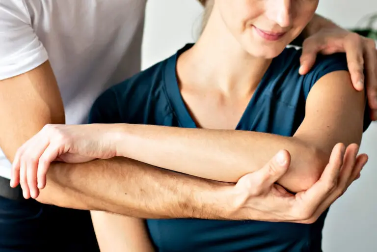 A physiotherapist from LiveWise Health assessing a lady's shoulder to treat her after she injured it.