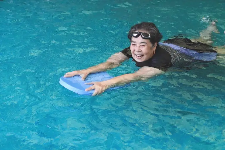 An asian lady happily swimming in the pool for hydrotherapy with the physiotherapist from LiveWise Health supervising off-camera.