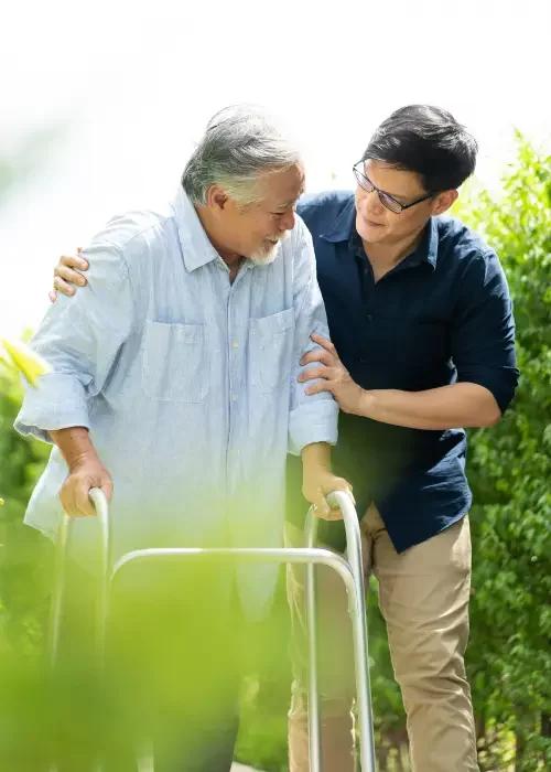 Mobile community physiotherapist from LiveWise Health assisting a senior Australian male to walk in his backyard.